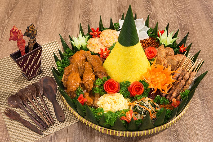 traditional yellow rice mountain served with chicken bumbu, keroppok, vegetables, peanuts