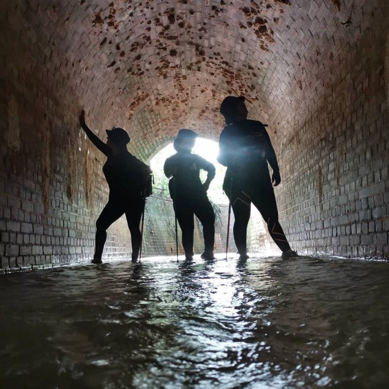three women posing in a tunnel which is also a drain